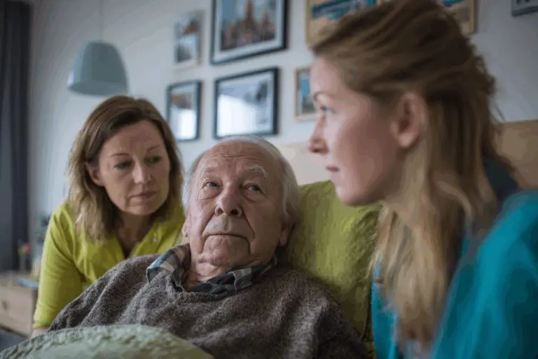 Ein älterer Mann im Bett, umgeben von seiner Tochter und Ehefrau – familiäre Nähe und Palliativpflege zuhause